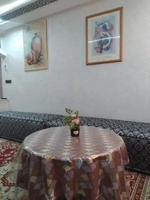 a table in a room with a couch and a table with flowers at Rooms in shared apartment close to CMN-Airport in Dah Hammou Ben Cheïkh