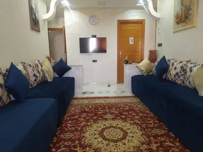 a living room with two blue couches and a television at Rooms in shared apartment close to CMN-Airport in Dah Hammou Ben Cheïkh
