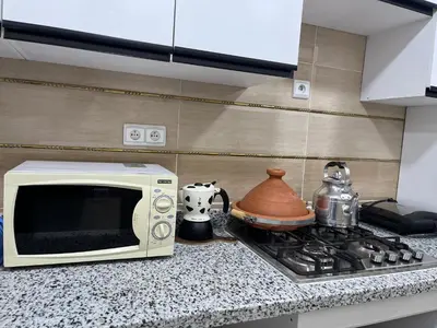 a microwave sitting on a counter next to a stove at Dar MAKTOUBE in Mohammedia