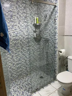 a bathroom with a glass shower with a toilet at Apparemment TAMARIS in Dar Bouazza