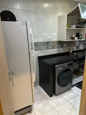 a kitchen with a black counter and a refrigerator at Apparemment TAMARIS in Dar Bouazza