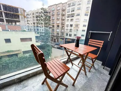 a wooden table and chairs on a balcony with a window at Modern Studio with Balcony & Parking Les Princesses 204 in Casablanca