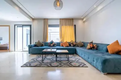 a living room with a blue couch and a table at Cosy 80 m2 with 2 balcony 5min Hassan 2 in Casablanca