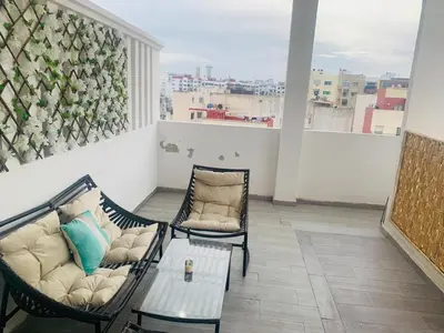 a living room with two chairs and a couch on a balcony at Cosy 80 m2 with 2 balcony 5min Hassan 2 in Casablanca