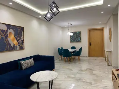 a living room with a blue couch and a table at Luxueux Appart à 5 min aéroport mohamed 5 in Nouaceur