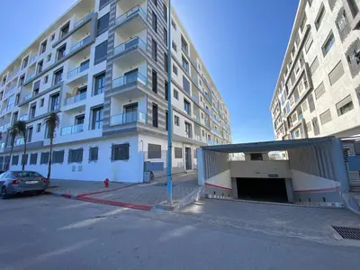 a large apartment building with a parking lot in front of it at Luxueux Appart à 5 min aéroport mohamed 5 in Nouaceur