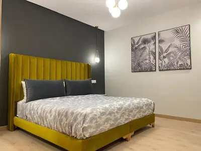 a bedroom with a yellow bed with three pictures on the wall at Luxueux Appart à 5 min aéroport mohamed 5 in Nouaceur