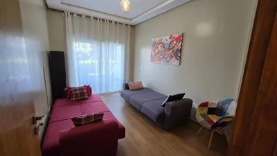 a living room with a couch and a bed and a chair at Le doux refuge - à 7 mn de la plage à pieds in Temara