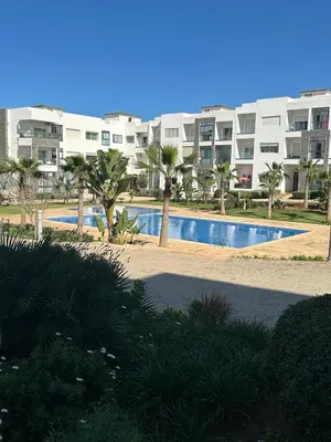 a swimming pool in front of a large apartment building at Le doux refuge - à 7 mn de la plage à pieds in Temara