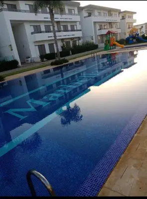 a swimming pool in front of a building at Marbella Beach Almansouria in Mansouria