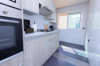 a kitchen with a counter with a stove and a window at Chic & Spacious : 3BR Apartment in Central Rabat in Rabat