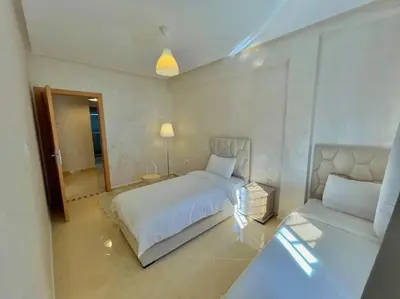 a bedroom with a white bed and a couch at F4 Appartement entièrement neuf au cœur de Témara in Temara