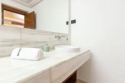 a white bathroom with a sink and a mirror at Aristocratic Abode: Luxurious 2BR Flat in Agdal in Rabat