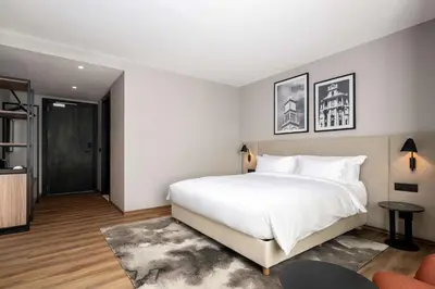 a bedroom with a large white bed and a chair at Radisson Hotel Casablanca Gauthier La Citadelle in Casablanca
