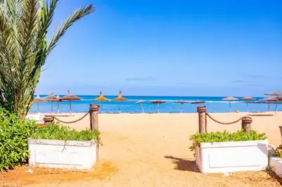 a sandy beach with umbrellas and the ocean at Magnifique oasis de détente ! in Bouznika