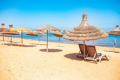 a group of straw umbrellas and chairs on a beach at Magnifique oasis de détente ! in Bouznika