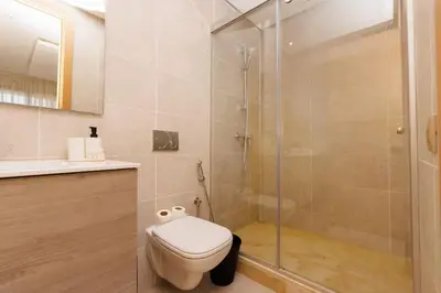 a bathroom with a toilet and a glass shower at Stylish 1BR flat in Hay Riad Central Rabat in Rabat