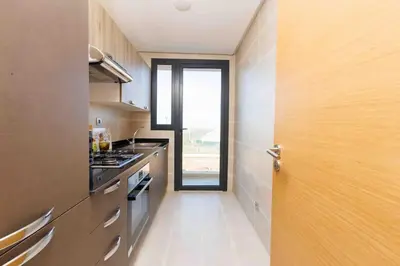 a kitchen with a door open to a kitchen with a stove at Central Charm: 1-Bed Apartment in Hay Riad in Rabat