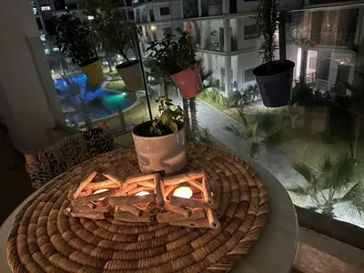 a table with a fire in a room with potted plants at Belle appartement tout neuf in Bouznika