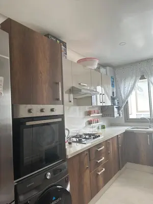 a kitchen with wooden cabinets and a stove top oven at Belle appartement tout neuf in Bouznika
