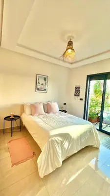 a white bedroom with a large bed and a window at Cozy 2 bedrooms flat at Dar Bouazza in Dar Bouazza