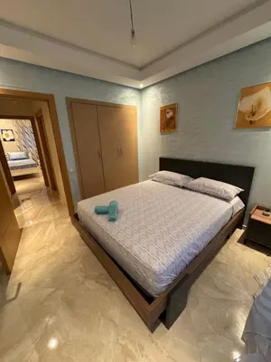 a bedroom with a bed with a blue object on it at Bouznika Beach appartement de luxe avec piscine in Bouznika