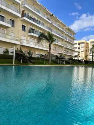 a swimming pool in front of a large building at Bouznika Beach appartement de luxe avec piscine in Bouznika