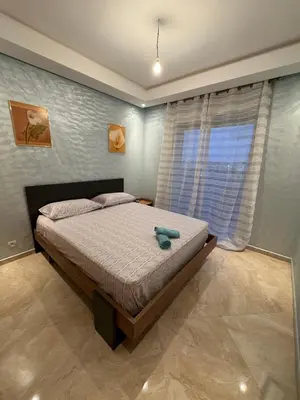 a bedroom with a bed and a large window at Bouznika Beach appartement de luxe avec piscine in Bouznika