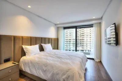 a bedroom with a white bed and a large window at Appart en face de la tour CFC in Casablanca