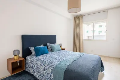 a bedroom with a bed with a blue comforter and a window at Charming apartment, in heart of Agdal, 2 rooms in Rabat