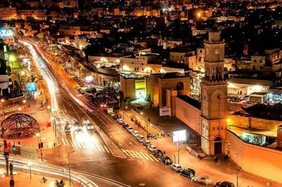 a city lit up at night with a clock tower at Appartement Panoramique in Casablanca