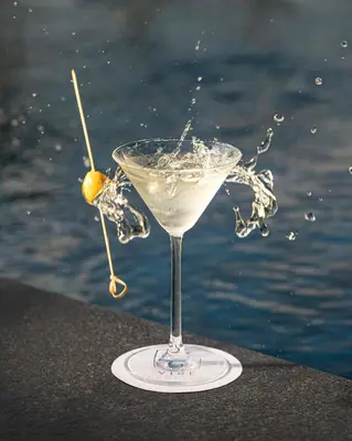 a martini glass with a green olive on a table near the water at Courtyard by Marriott Casablanca Downtown in Casablanca