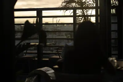 a person sitting in a chair looking out a window at the sunset at Courtyard by Marriott Casablanca Downtown in Casablanca