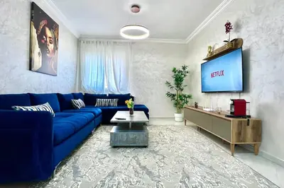 a living room with a blue couch and a tv at T6 Appartement entièrement neuf au cœur de Témara in Temara