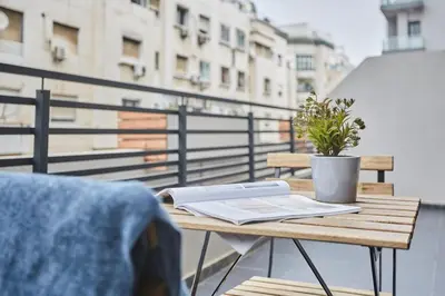 a table with a book and a plant on a balcony at Chic and Cozy 1 Bedroom Oasis in the Heart of Casa in Casablanca