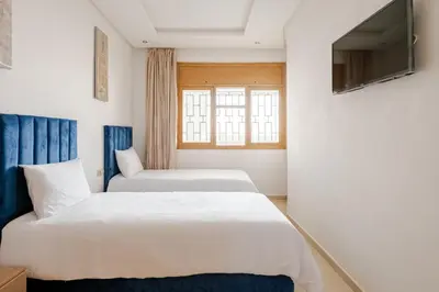 two beds in a room with a tv on a wall at New Luxurious apartment Agdal Rabat center in Rabat