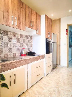 a kitchen with wooden cabinets and a refrigerator at Appartement Cosy Agdal Centre Rabat in Rabat
