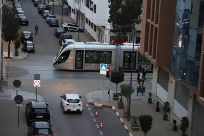 a train traveling down a city street with cars at Appartement Cosy Agdal Centre Rabat in Rabat