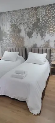 two white beds in a bedroom with a wall at Eden Room SCH in Rabat