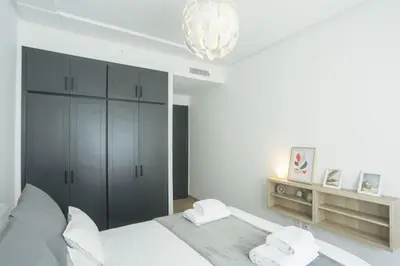 a white bedroom with a bed and a chandelier at Résidence Windsor in Casablanca