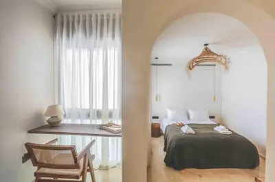 a bedroom with a bed and a table and a chair at Résidence La Fontaine - Racine in Casablanca