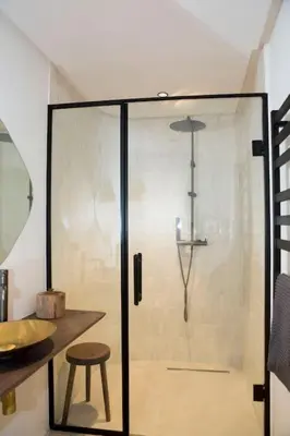 a glass shower with a stool in a bathroom at Résidence La Fontaine - Racine in Casablanca