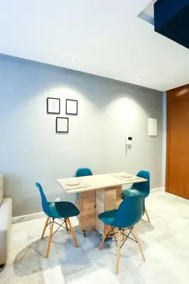 a dining room with a table and blue chairs at Résidence B-Livin - La Ferme Bretonne in Casablanca