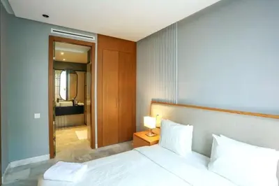 a bedroom with a white bed with a lamp on a table at Résidence B-Livin - La Ferme Bretonne in Casablanca
