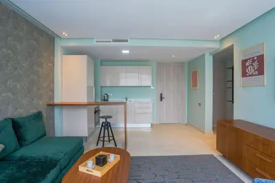 a living room with a green couch and a kitchen at Résidence Anfa Sunset - Ain Diab Casablanca Beach in Casablanca