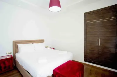 a bedroom with a white bed and a red stool at Résidence Urban Square F26 in Casablanca