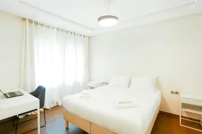 a white bedroom with a bed and a desk at Résidence Urban Square D52 in Casablanca