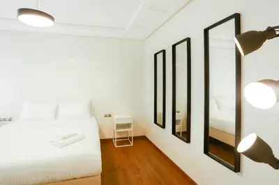 a white bedroom with a bed and a mirror at Résidence Urban Square D52 in Casablanca