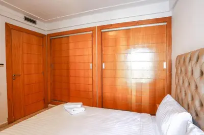 a bedroom with a bed with wooden closet doors at Résidence Smalto - Bd Anfa in Casablanca