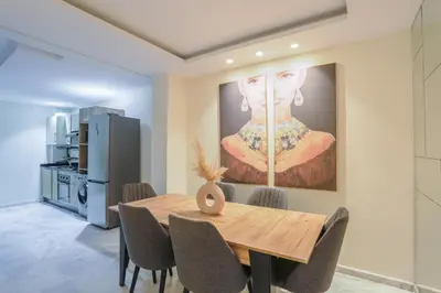 a dining room with a table and a painting on the wall at Résidence Marie Césaire - Maarif in Casablanca